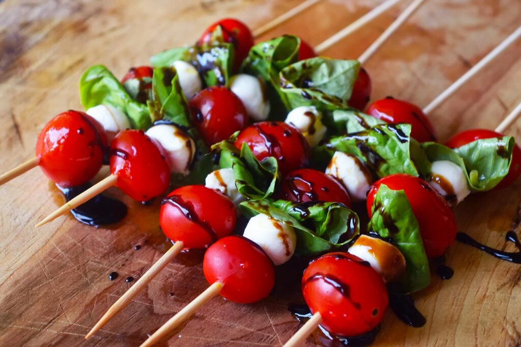 A closeup of a row of Caprese Skewers drizzled with balsamic glaze.