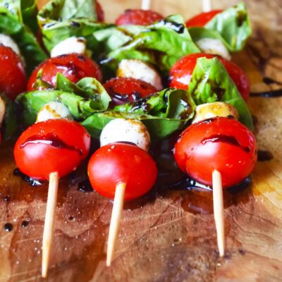 A front view of a row of Caprese Skewers laying on a wood surface.