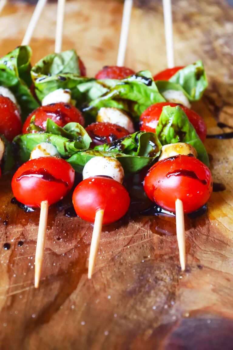 A front view of a row of Caprese Skewers laying on a wood surface.