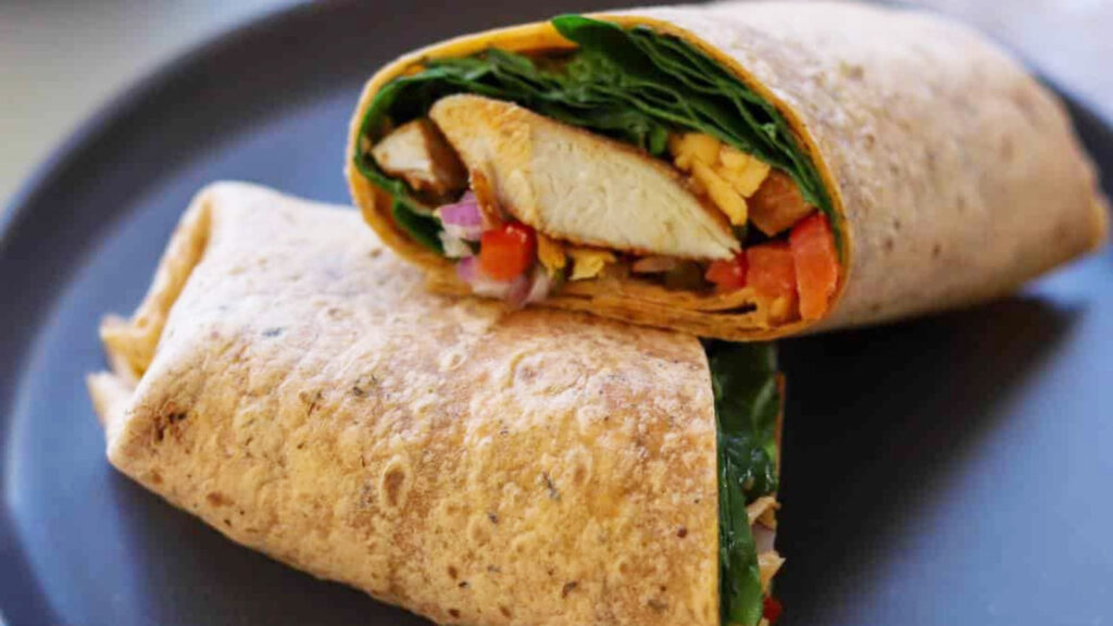 A cut, chicken spinach wrap laying on a plate.