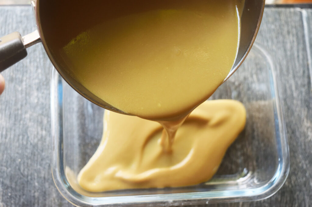 Pouring coffee ice cream batter into a freezer-safe container.
