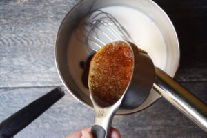 Pouring honey into a pot of oat milk.