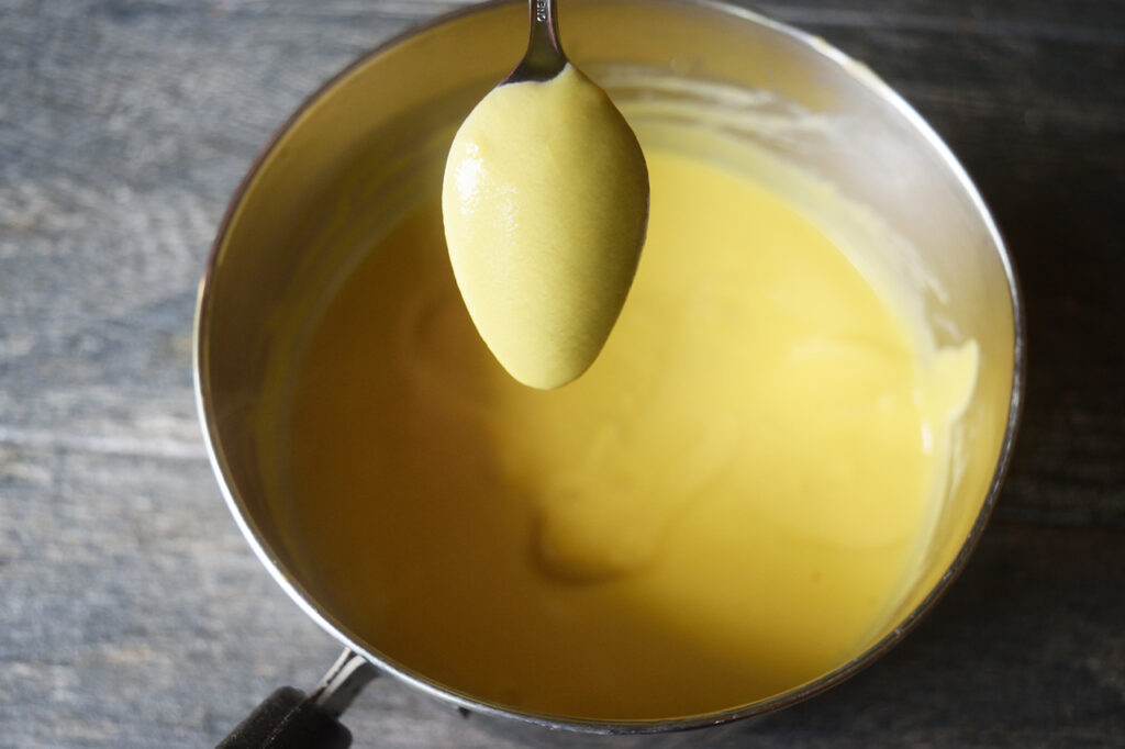 The back of a spoon coated in custard for making coffee ice cream.