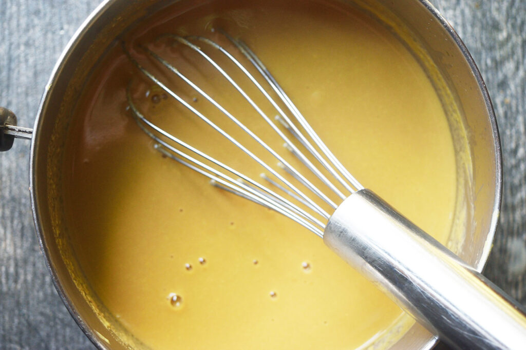 Finished coffee ice cream batter resting in a pot with a whisk.