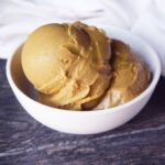 Scoops of coffee ice cream in a white bowl on a gray surface.