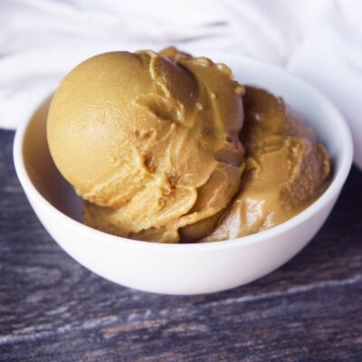 Scoops of coffee ice cream in a white bowl on a gray surface.