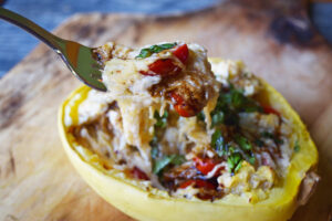 A fork lifts a forkful of creamy stuffed spaghetti squash from a squash half.