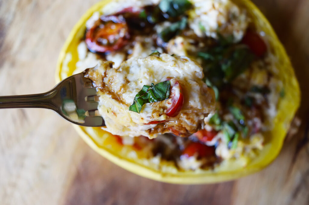 An overhead view of a fork lifting up a forkful of creamy stuffed spaghetti squash.