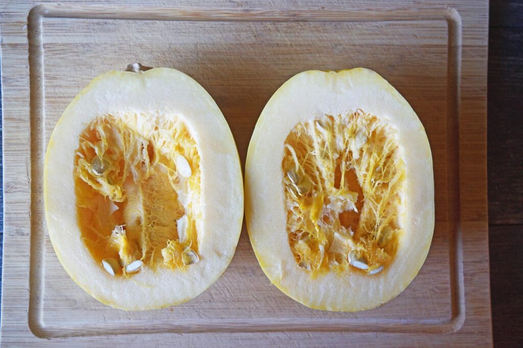 Two spaghetti squash halves on a cutting board.