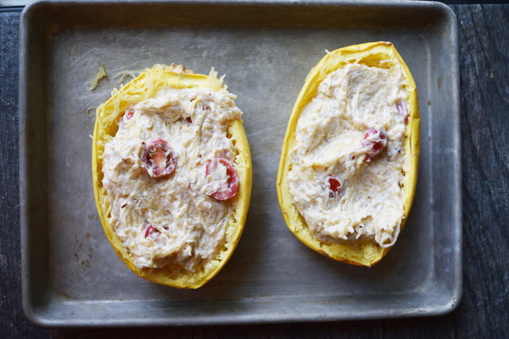 Filling returned to two spaghetti squash halves on a baking sheet.