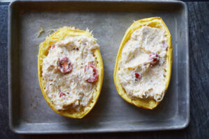 Filling returned to two spaghetti squash halves on a baking sheet.