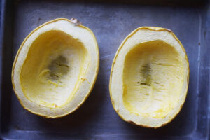 Two baked spaghetti squash halves on a baking sheet.