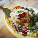 side view of a fork lifting up some creamy stuffed spaghetti squash from a squash half.