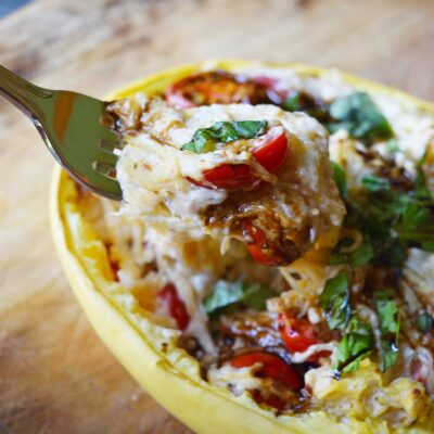 side view of a fork lifting up some creamy stuffed spaghetti squash from a squash half.