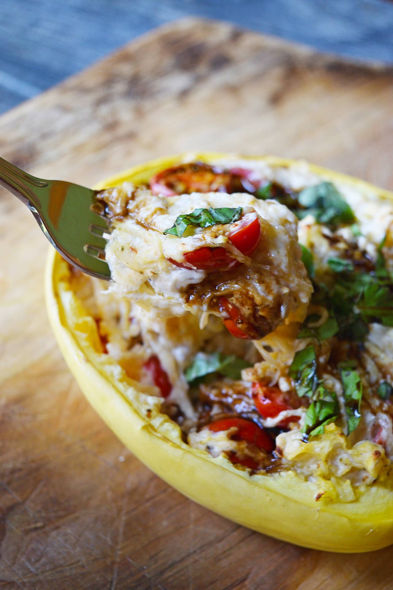side view of a fork lifting up some creamy stuffed spaghetti squash from a squash half.