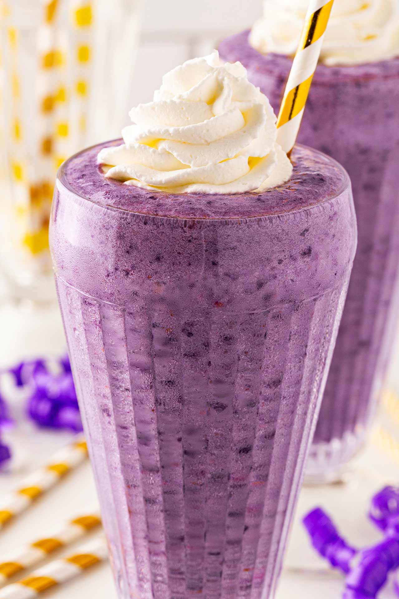A tall glass filled with Grimace Shake and topped with whipped cream.