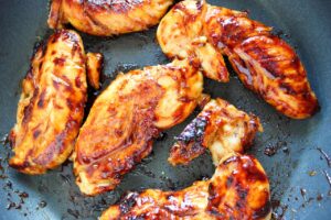 Honey Mustard Chicken Tenders cooking in a skillet.