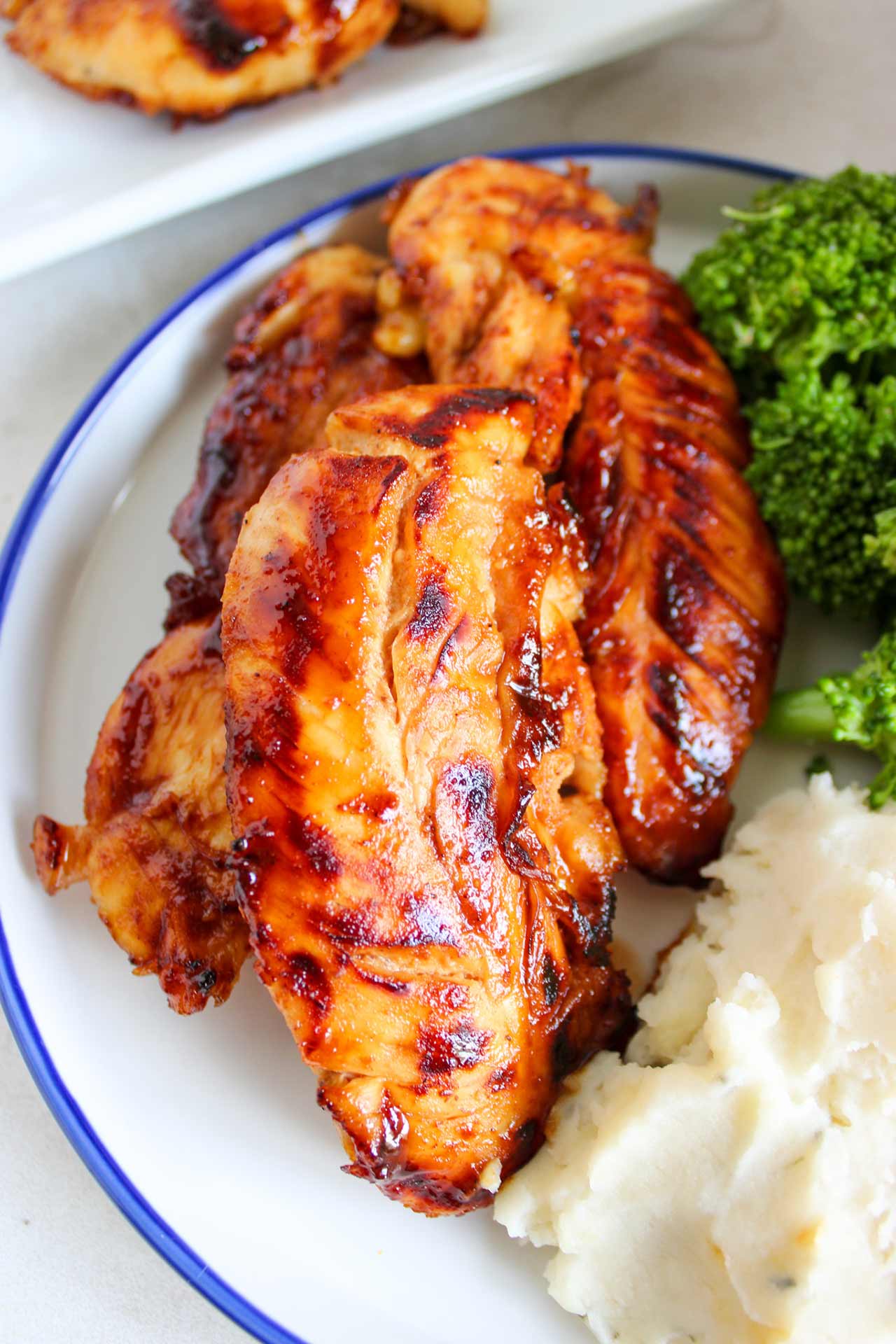 A closeup of honey mustard chicken tenders on a plate with mashed potatoes and broccoli.