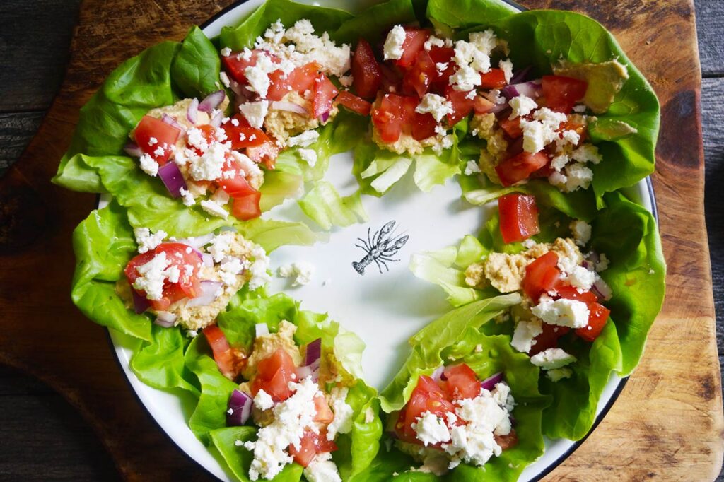 Feta cheese sprinkled over Mediterranean Lettuce Wraps on a white platter.