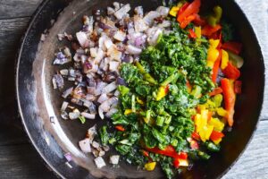 Sautéd onions with frozen spinach and bell peppers in a cast iron skillet.