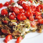 A front view of a Mediterranean Omelet on a white plate topped with tomatoes and feta.