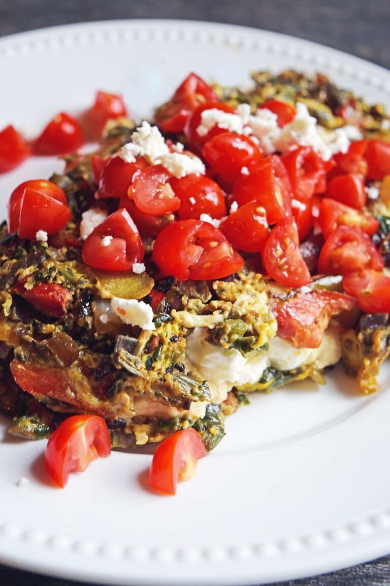 A front view of a Mediterranean Omelet on a white plate topped with tomatoes and feta.