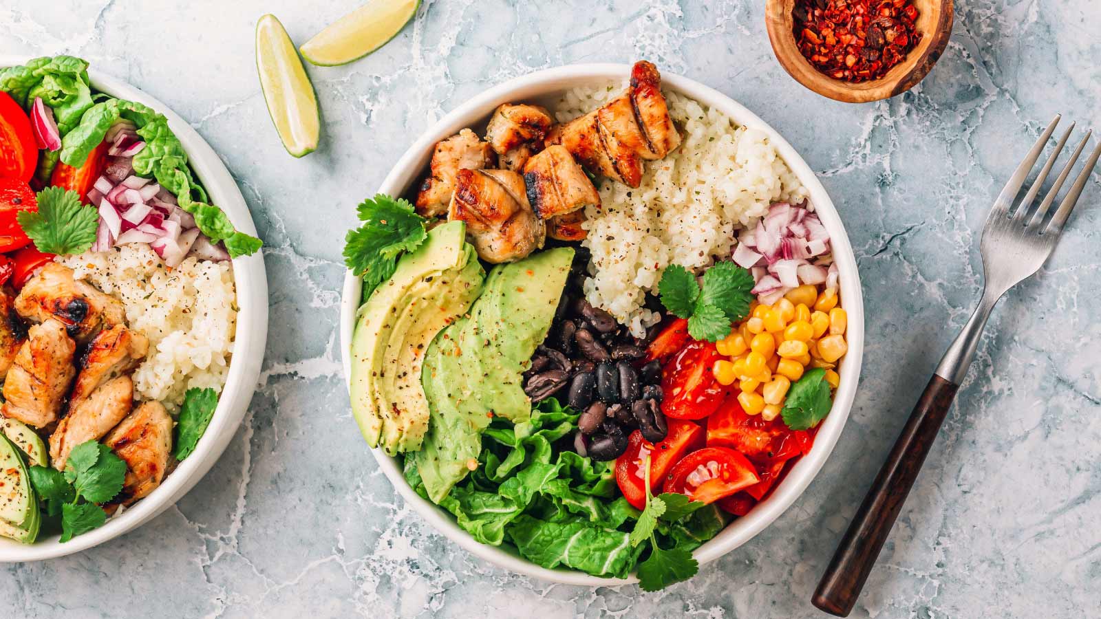 Mexican chicken burrito bowl with rice, beans, tomato, avocado,corn and lettuce.
