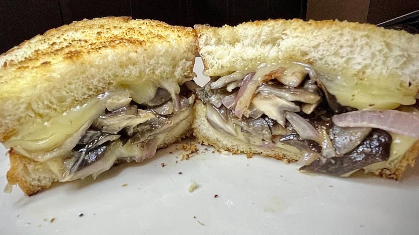 A closeup of a cut mushroom grilled cheese sandwich.