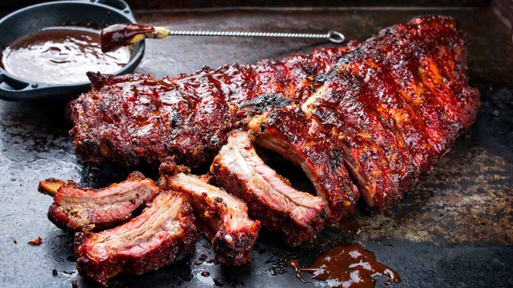 Baby back pork ribs St Louis cut with marinade as closeup on an old rustic board.