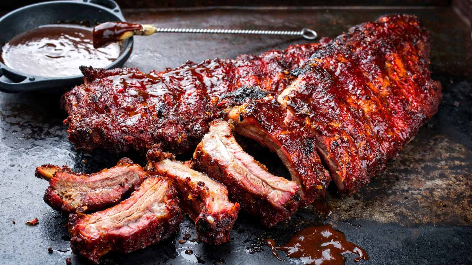 Baby back pork ribs St Louis cut with marinade as closeup on an old rustic board.