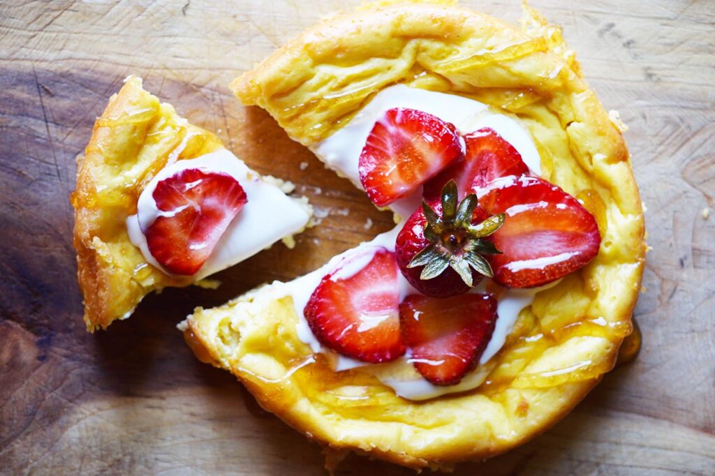 An overhead view of a slice of. yogurt cake sitting back from the cake on a wood surface.