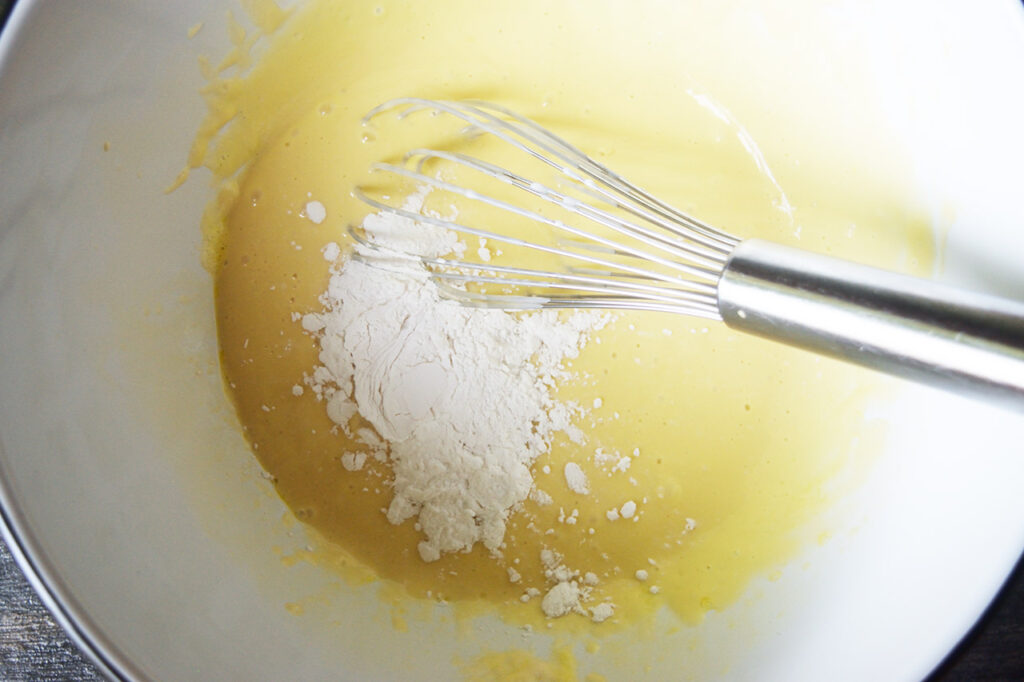 Arrowroot powder added to yogurt cake batter in a mixing bowl.