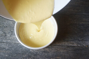 Pouring yogurt cake batter into a cake pan.