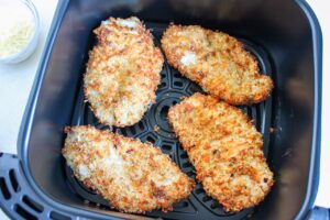 Crisp, breaded chicken breasts in an air fryer basket.