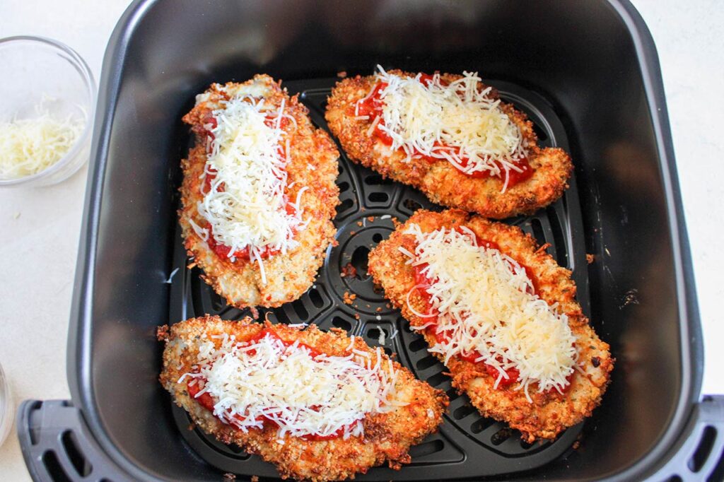 Air Fryer Chicken Parmesan breasts in an air fryer basket.