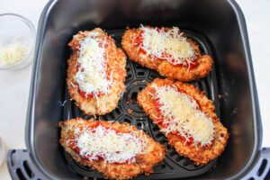 Air Fryer Chicken Parmesan breasts in an air fryer basket.
