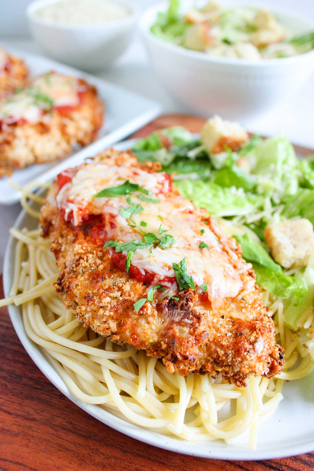 Front closeup focus of a bread of Air Fryer Chicken Parmesan on a bed of spaghetti noodles.