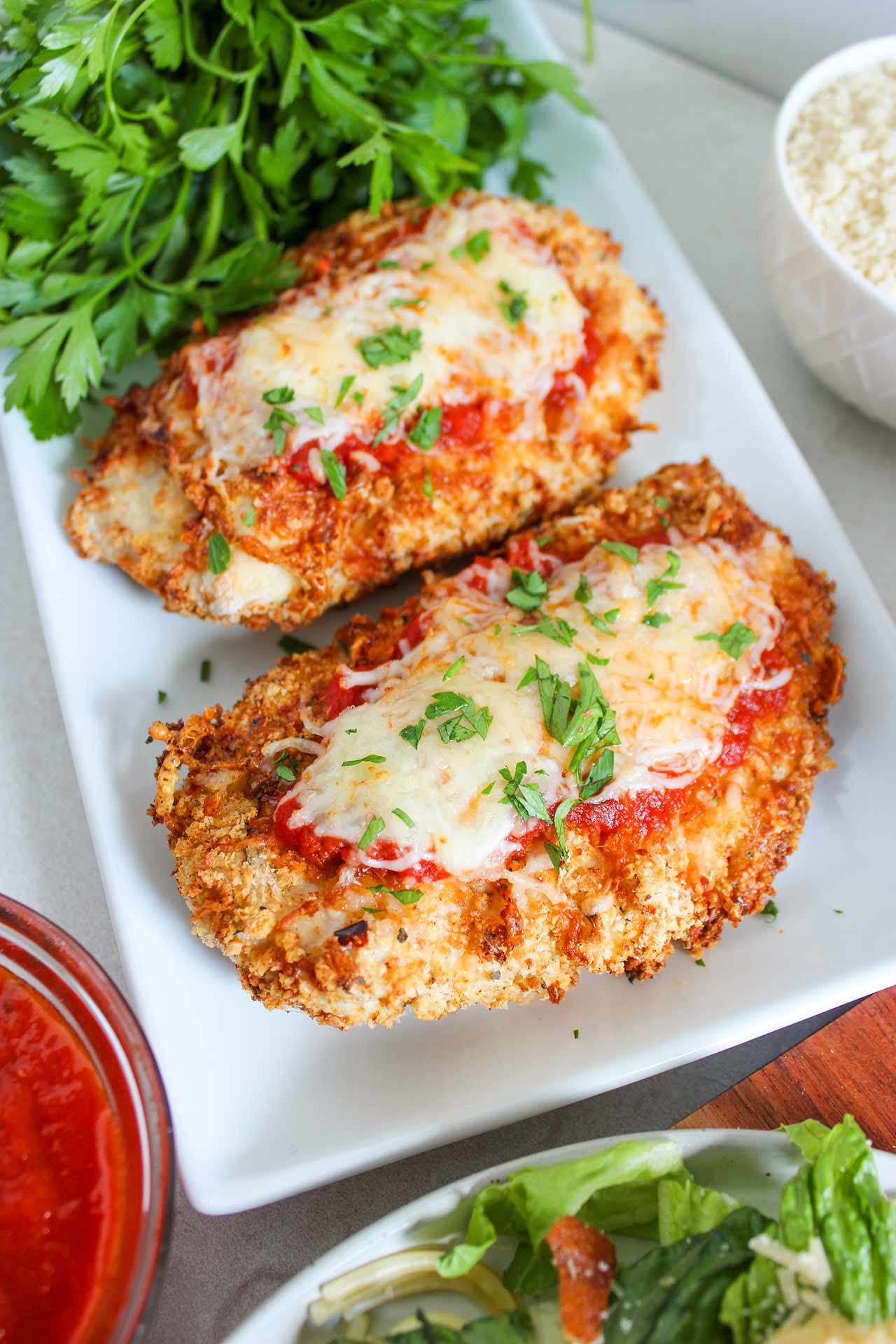 Two breasts of Air Fryer Chicken Parmesan on a white platter.