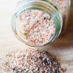 Closeup view of an open spice jar on it's side with blackening seasoning spilling out.