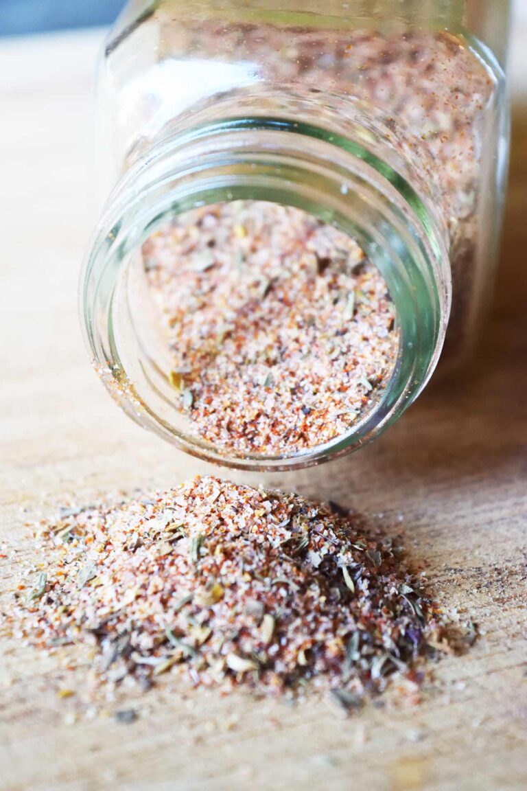 Closeup view of an open spice jar on it's side with blackening seasoning spilling out.
