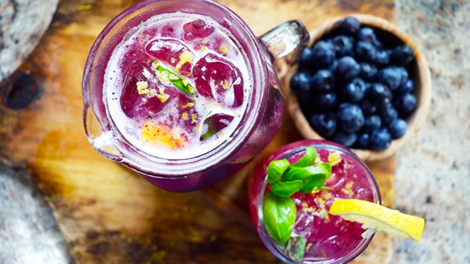 An overhead view of a glass pitcher and a glass next to each other, both filled with Blueberry Lemonade.