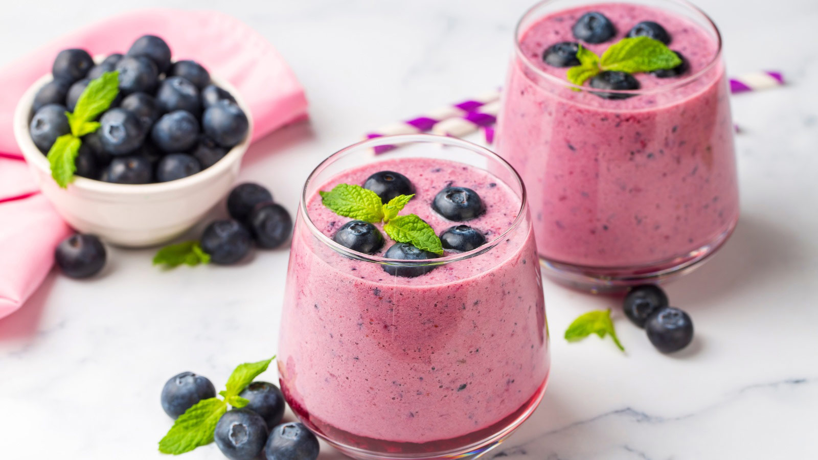 Glass of blueberry smoothie with mint and fresh berries.