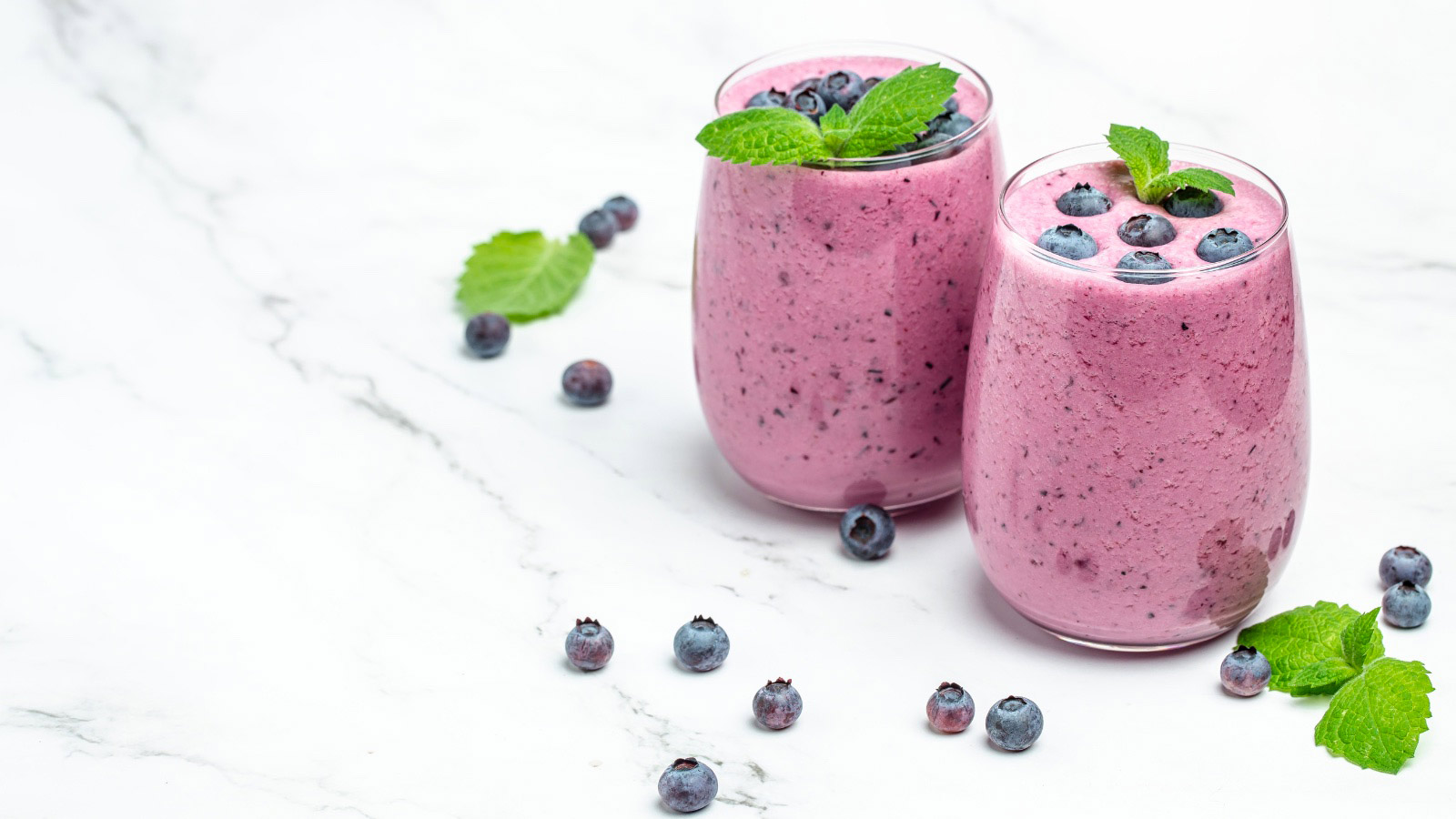 Two glasses of fresh blueberry smoothies.