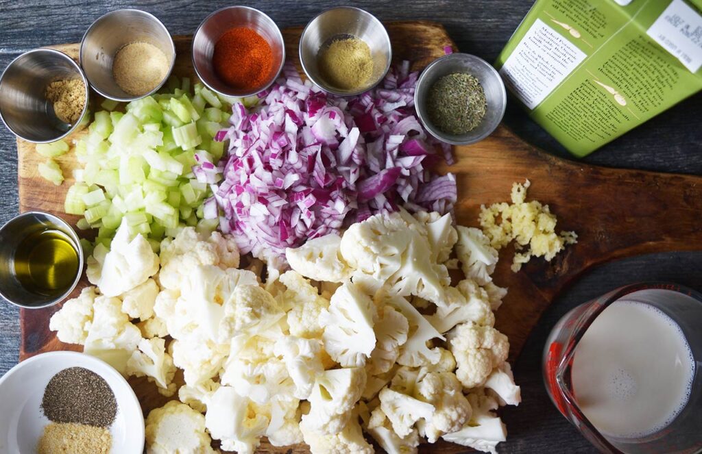 Ingredients for Cauliflower Soup gathered on a wood cutting board.