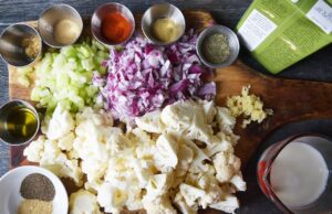 Ingredients for Cauliflower Soup gathered on a wood cutting board.