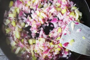 Celery and chopped red onions saut&eacute;ing in a skillet.
