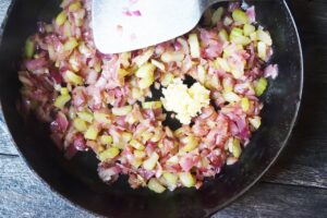 Garlic added to a skillet of saut&eacute;ing veggies.