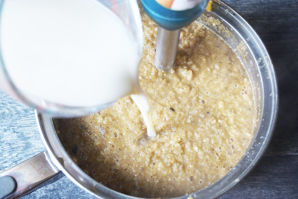 Pouring milk into blended cauliflower soup.