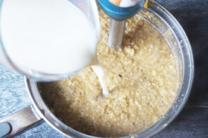 Pouring milk into blended cauliflower soup.