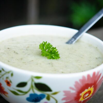 A bowl of Cauliflower Soup on a wood surface.